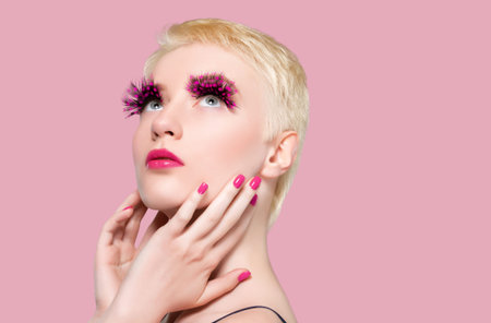 Portrait of a beautiful woman with short blonde hair, with false feather eyelashes, with pink...