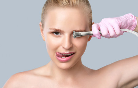 Beautiful young blonde woman with nude makeup, clean fresh skin naked shoulders holds a nozzle for...