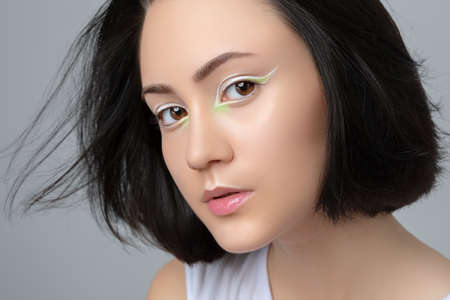Portrait of a beautiful teenage girl with dark hair, with beautiful creative white makeup and healthy clean skin. Makeup and cosmetology concept.の写真素材