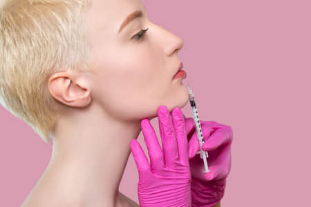 Woman with beautiful clean skin. Cosmetologist does injections for lips augmentation and anti wrinkle of a beautiful woman. Women's cosmetology in the beauty salon.の写真素材