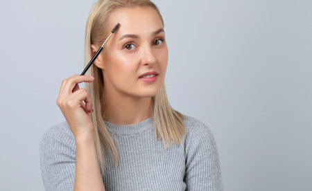 A girl combs her eyebrows with a brush after dyeing in a beauty salon.Professional makeup and...
