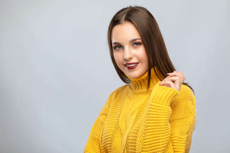 Brunette girl with beautiful makeup, with clean skin, long hair in a yellow winter sweater. New Year conceptの写真素材