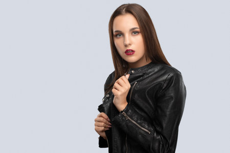 Brunette girl with beautiful makeup, with clean skin, long hair in a black leather jacket.の写真素材