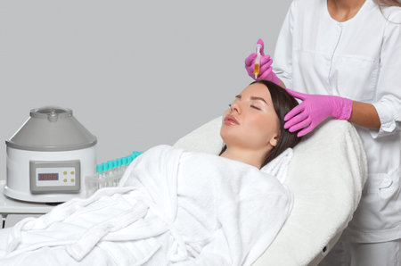 Cosmetologist does prp therapy against hair loss of a beautiful woman in a beauty salon. Cosmetology...