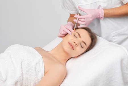 Cosmetologist makes rejuvenating anti wrinkle injections on the face of a beautiful woman. Female aesthetic cosmetology in a beauty salon.の写真素材