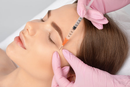 Cosmetologist makes rejuvenating anti wrinkle injections on the face of a beautiful woman. Female...