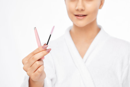 Young attractive woman in a white coat plucking eyebrows. Professional make-up and cosmetic skin...