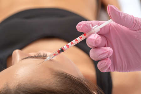 Cosmetologist makes rejuvenating anti wrinkle injections on the face of a beautiful woman. Female aesthetic cosmetology in a beauty salon.の写真素材