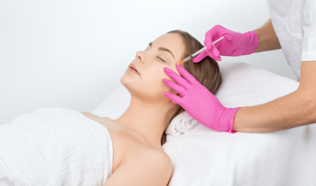 Cosmetologist makes rejuvenating anti wrinkle injections on the face of a beautiful woman. Female aesthetic cosmetology in a beauty salon.の写真素材