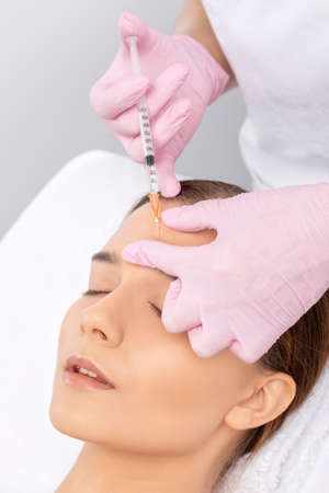 Cosmetologist makes rejuvenating anti wrinkle injections on the face of a beautiful woman. Female aesthetic cosmetology in a beauty salon.の写真素材