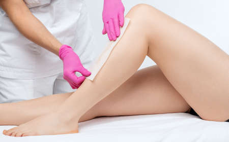 A beautician makes a sugar paste depilation of a woman's legs in a beauty salon. Female aesthetic cosmetology.の写真素材