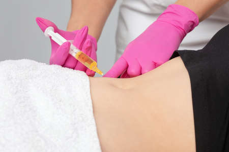 Aesthetic cosmetology doctor makes injections against stretch marks on the woman's abdomen and body. Women's aesthetic cosmetology in a beauty salon.の写真素材