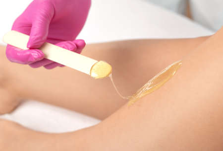 A beautician makes a sugar paste depilation of a woman's legs in a beauty salon. Female aesthetic cosmetology.の写真素材