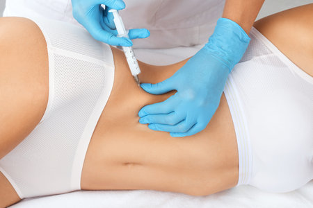 cosmetologist makes lipolytic injections to burn fat on the stomach and waist of a woman. Female...