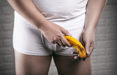 A man in white underwear holds a banana, symbolizing problems with male sexuality.