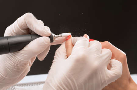 The master of the manicure saws and attaches a nail shape during the procedure of nail extensions in the beauty salon. Professional care for hands.の写真素材