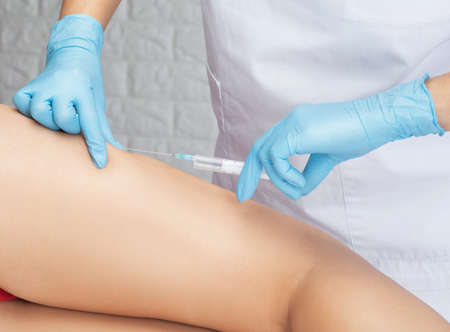 Aesthetic cosmetologist makes lipolytic injections to burn fat on the thighs, hips and body of a woman. Female aesthetic cosmetology in a beauty salon.Cosmetology concept.の写真素材