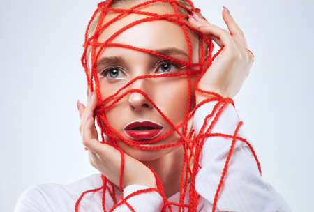 Portrait of a beautiful girl with delicate makeup with red threads all over her face.の写真素材