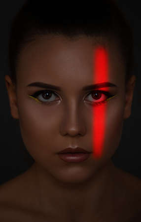 Portrait of an attractive girl with healthy clean skin and beautiful makeup on a dark background, there is a red stripe on her face.の写真素材