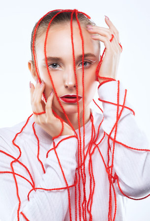 Portrait of a beautiful girl with delicate makeup with red threads all over her face.