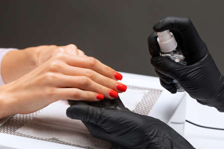 The master of the manicure saws and attaches a nail shape during the procedure of nail extensions in the beauty salon. Professional care for hands.の写真素材