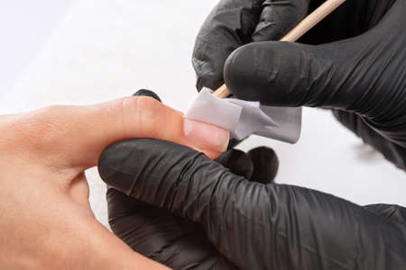 A manicurist removes cuticles during a nail extension procedure in a beauty salon. Professional hand care.の写真素材