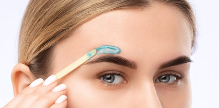 Makeup artist does facial hair removal procedure. Beautiful girl with blue eyes having Permanent...