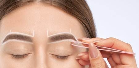 Make-up artist makes markings with white pencil for eyebrow and paints eyebrows. Professional makeup...