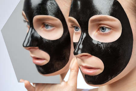 Cosmetologist doing carbon peeling procedure to beautiful blue-eyed girl in a beauty salon. hardware cosmetology treatment.の写真素材