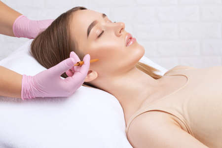 Cosmetologist makes rejuvenating anti wrinkle injections on the face of a beautiful woman. Female aesthetic cosmetology in a beauty salon.の写真素材