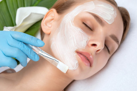Beautician makes a face mask of a woman to rejuvenate the skin. Cosmetology treatment of problem...