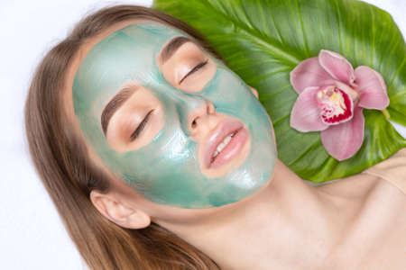 Beautician makes a face mask of a woman to rejuvenate the skin. Cosmetology treatment of problem skin on the face and body.の写真素材