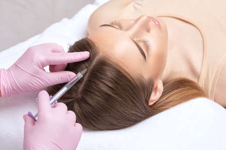 Cosmetologist does injections therapy against hair loss and anti-dandruff of a beautiful woman in a beauty salon. Cosmetology concept.の写真素材