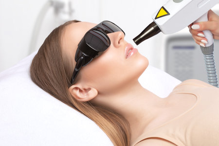 Beautician does Laser tattoo removal to a beautiful woman. Hardware cosmetology treatment in the beauty salon.の写真素材