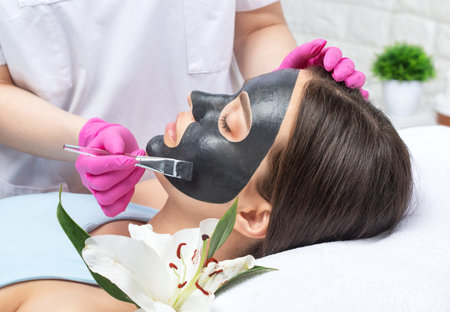 Cosmetologist doing carbon peeling procedure to beautiful blue-eyed girl in a beauty salon. hardware cosmetology treatmentの写真素材