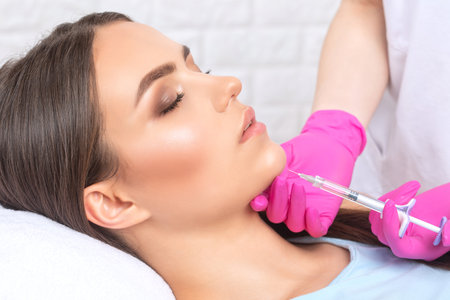 Cosmetologist makes rejuvenating anti wrinkle injections on the face of a beautiful woman. Female aesthetic cosmetology in a beauty salon.の写真素材