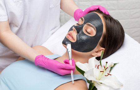 Cosmetologist doing carbon peeling procedure to beautiful blue-eyed girl in a beauty salon. hardware cosmetology treatmentの写真素材