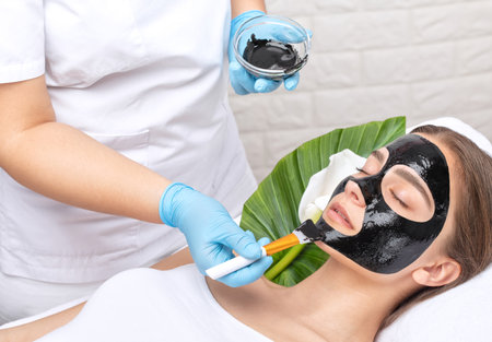 Cosmetologist doing carbon peeling procedure to beautiful blue-eyed girl in a beauty salon. hardware cosmetology treatment.の写真素材