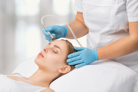 Cosmetologist makes procedure microdermabrasion on the face against acne and blackheads near the eyes. Women's cosmetology in the beauty salon.の写真素材