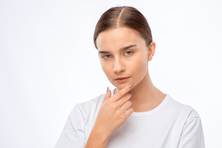 Beautiful young pensive woman with clean skin in a white t-shirt. Makeup and healthy clear skin.の写真素材