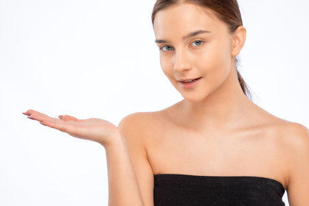 Beautiful young woman with clean skin and a beautiful smile shows something. Makeup and healthy clear skin.の写真素材