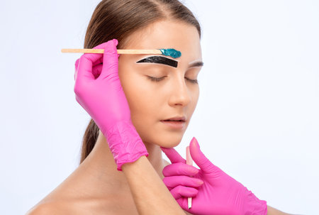 The make-up artist makes markings with a white eyebrow pencil and applies paint on the eyebrows. Professional make-up and face care.の写真素材