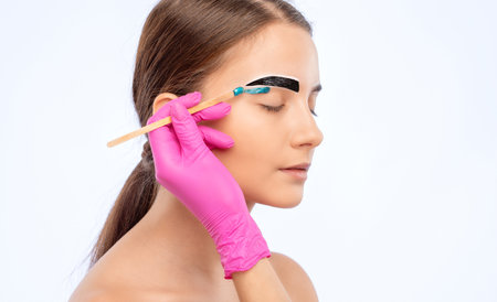 The make-up artist makes markings with a white eyebrow pencil and applies paint on the eyebrows. Professional make-up and face care.の写真素材
