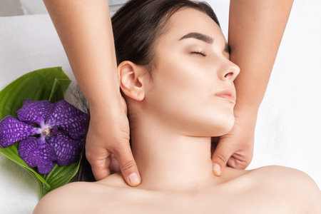 Masseur makes a relaxing massage on the face, neck, shoulders and collarbones of a young beautiful woman in a spa. Cosmetology and massage concept.の写真素材