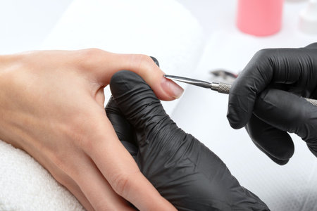 A manicurist removes cuticles during a nail extension procedure in a beauty salon. Professional hand care.の写真素材