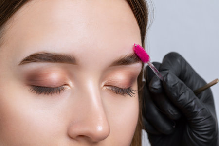 The make-up artist makes markings with a white eyebrow pencil and applies paint on the eyebrows. Professional make-up and face care.の写真素材
