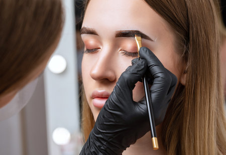 The make-up artist does Long-lasting styling of the eyebrows of the eyebrows and will color the eyebrows. Eyebrow lamination. Professional make-up and face care.の写真素材