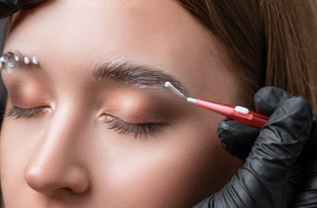 The make-up artist makes markings with a white eyebrow pencil and applies paint on the eyebrows. Professional make-up and face care.の写真素材