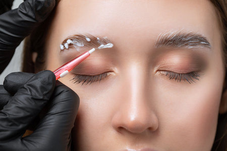 The make-up artist does Long-lasting styling of the eyebrows and will color the eyebrows. Eyebrow lamination. Professional make-up and face care.の写真素材