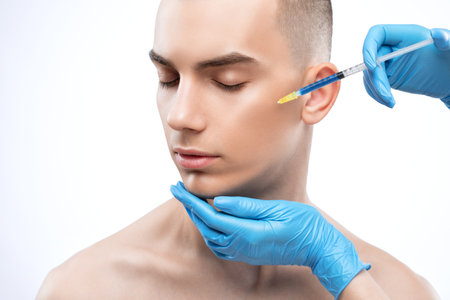 Men's cosmetology. Beautician makes a man a rejuvenation injection procedure on his face.の写真素材